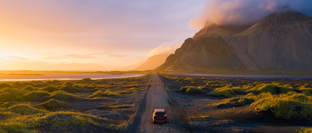 Car driving along a scenic road at sunset.