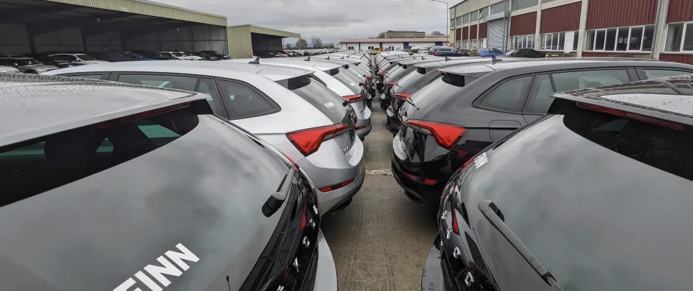 Rows and rows of cars with FINN logo stickers on them at a compound.