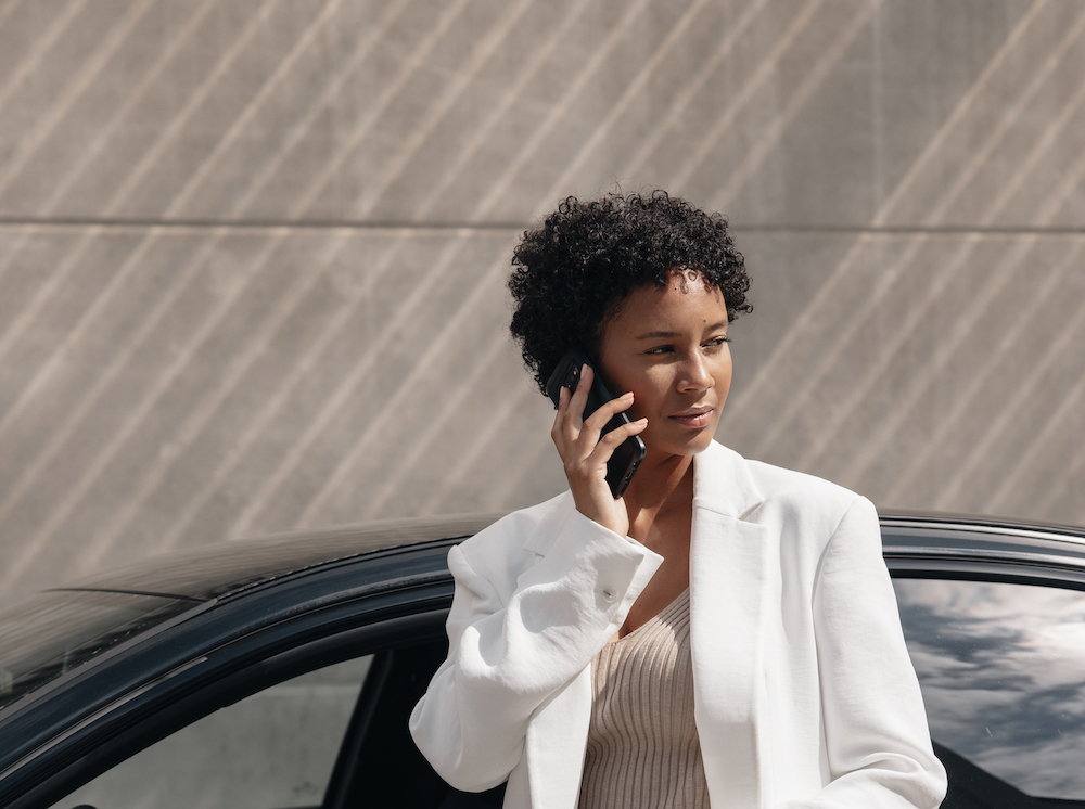 Person standing next to a car holding a phone to their ear